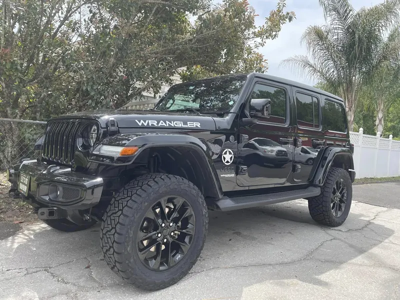 Black Jeep Wrangler on black wheels and all-terrain tires