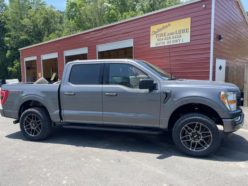 Gray Ford F-150 FX4 in front of the four open bays and the Callahan Tire and Lube sign
