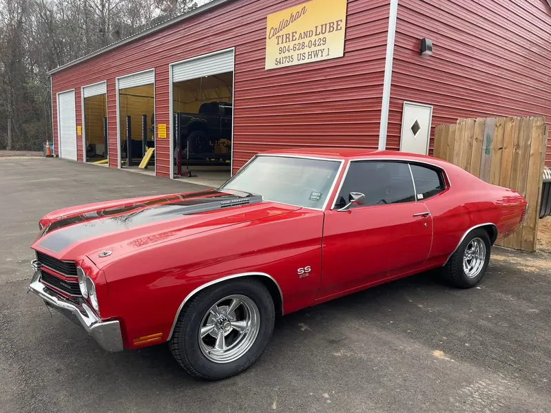 Red Chevelle SS with black stripes on new chrome wheels, in front of the four open bays and the Callahan Tire and Lube sign