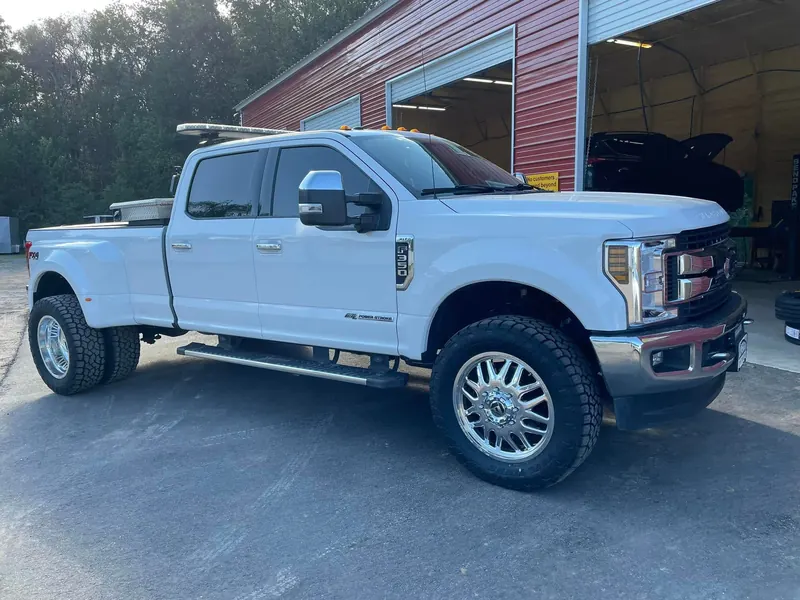 White Ford F-350 dually with a 3-inch level kit, 22-inch Fuel wheels and Toyo all-terrain tires, at the open bays
